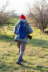 Mature hunter man holding a shotgun and walking through a field