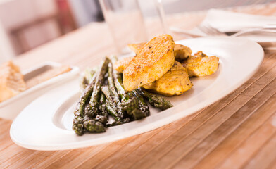 Fried chicken breast pieces with asparagus on white plate
