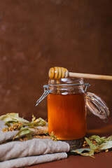 A jar of honey with dry linden leaves