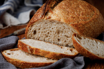 Traditional wheat freshly baked rustic bread on a towel. Artisan sourdough bread with a knife.