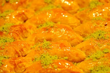 Close-up view of baklava with pistachios, walnuts and cream in a dessert shop selling traditional Turkish desserts. Şöbiyet, nightingale's nest, bird's eye baklava. Turkish culinary delights. Dessert 