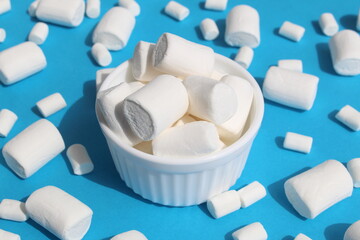 White marshmallow in a white cup is on a blue background.