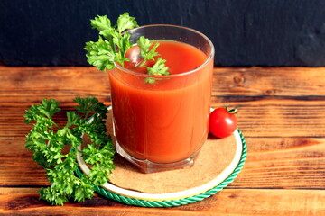 One glass with tomato juice stands on a wooden table.