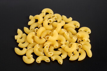 Pasta in a pile lies on a black background.