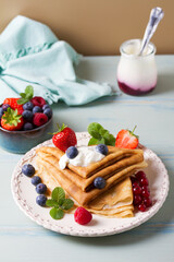 Crepes, thin pancake stack with yogurt and berries. Wrapped pancakes on a plate