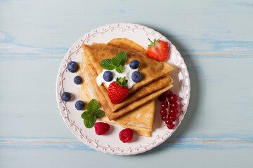 Crepes, thin pancake stack with yogurt and berries. Wrapped pancakes on a plate with copy space. High angle view