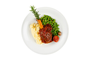 Lamb shank with sauce isolated on white background. Lamb shank served with mashed potatoes and peas in an elegant presentation.