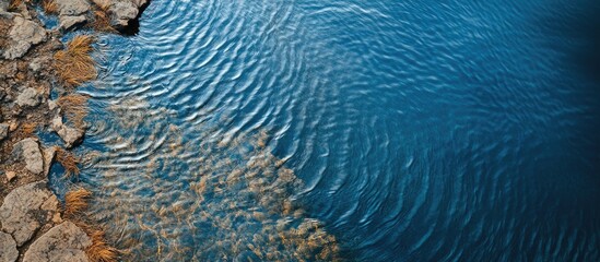 Aerial view of crystal clear blue water reservoir with ripples and rocky shoreline capturing natural beauty and tranquility in landscape.