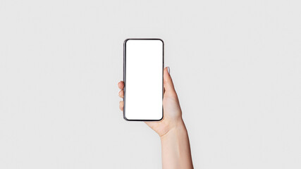 Female hand holding smartphone with empty screen on light background, closeup. Blank space for your design. Panorama