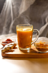 Steaming cup of herbal tea on wooden tray. Cozy atmosphere for winter evening. Concept of relax and didgital detox at home