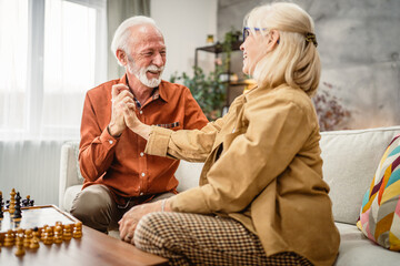 senior couple husband and wife play leisure chess board game at home