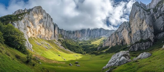 Naklejka premium Majestic cliffs of Asturias with lush green valleys under a dramatic cloudy sky showcasing natural beauty and geological formations.
