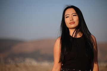 Fototapeta premium A joyful young Asian woman embraces the breathtaking beauty of her surroundings during the golden hour. 