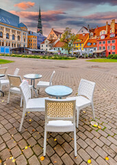 Outdoor street's coffee shop with tables and chairs in historical center of old European city, autumnal time indicated with yellow fallen leaves