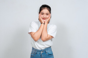 A studio portrait of a young Asian Indonesian woman looks happy as she smiles while her hands are...