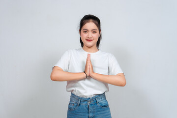 Smiling young Asian woman gesturing traditional greeting isolated over white background