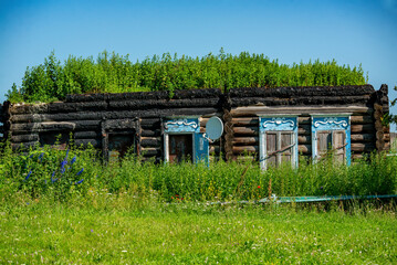 An old log cabin complete with a satellite dish perched on its roof