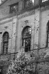 A black and white photo of a brick building with arched windows