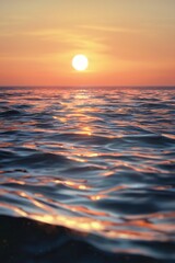 The horizon is a vast expanse of water, with the sun setting in the distance, casting an orange glow over its surface