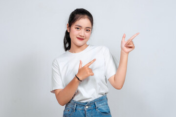 Excited Asian woman pointing at the copy space beside her, isolated on white background