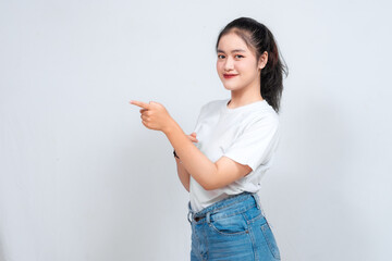 Excited Asian woman pointing at the copy space beside her, isolated on white background