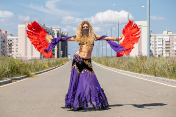 Sexy beautiful woman in a purple costume dances on the street