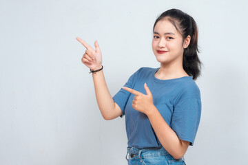 Excited Asian woman pointing at the copy space beside her, isolated on white background