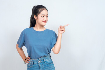 Excited Asian woman pointing at the copy space beside her, isolated on white background