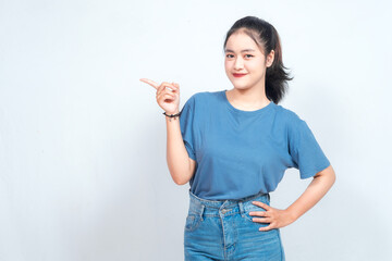 Excited Asian woman pointing at the copy space beside her, isolated on white background