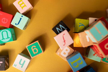 Colorful wooden alphabet blocks scattered on a yellow surface Learning and playing