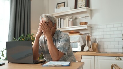 Stressed senior businessman holding head and thinking about solution while suffering from job...