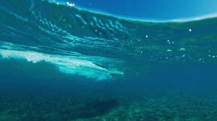 Sportswoman wearing a blue wetsuitis surfing on a longboard. Maldives