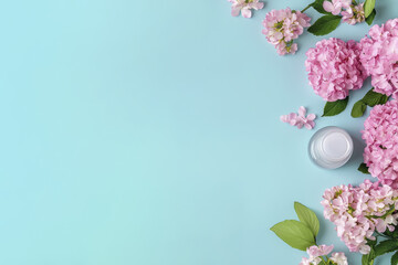 Luxurious skincare cream surrounded by pink hydrangeas and lilacs on blue background, creating serene and refreshing atmosphere