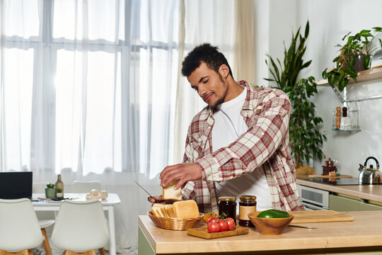 A young man slices bread and garnishes a sandwich in a sunny kitchen filled with plants.