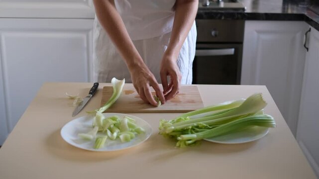 woman cutting celery stalks on a wooden board
