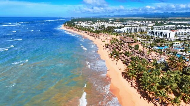 Sunny summer beach on golden sand coast with many resort hotels. Summer vacation and tourism. Sea bay beach background. Blue ocean waves on yellow sand, aerial view. Sea travel concept.