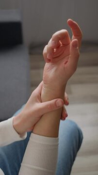 Vertical video of female suffer from numbing pain in hand, numbness fingertip, arthritis inflammation, peripheral neuropathies, woman massage hand with wrist pain. Rheumatoid arthritis concept