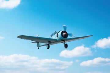 Naklejka premium A blue airplane is flying in the sky. The sky is clear and blue with a few clouds