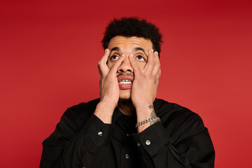 Young man shows a range of emotions while posing with a bold expression against red backdrop.