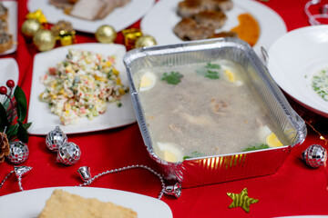 Traditional aspic (meat jelly) with boiled eggs and herbs in a foil container on a festive table...