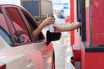Asian man receives burger and soda snacks in his car during rush hour from female valet at...