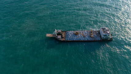 A ship is carrying a backhoe in the sea.