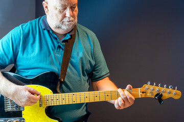 Older man learning to play guitar and strumming a G chord.