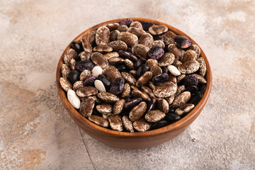 wooden bowl with Kidney beans on brown concrete, side view, close up