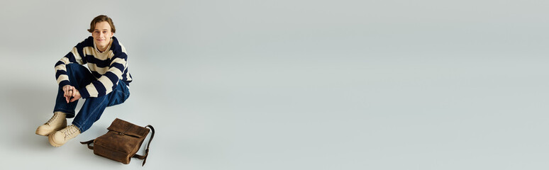 Handsome student enjoys quiet moment in a studio, dressed casually in fashionable attire, banner