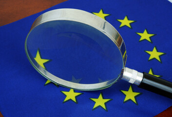 Magnifying glass on European Union flag close-up.