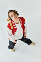 A fashionable young man in a bomber jacket stands confidently in a studio, embodying youth culture.