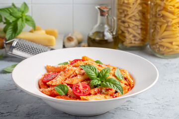 Classic italian pasta penne alla arrabiata with basil and freshly grated parmesan cheese on dark table. Penne pasta with chili sauce arrabbiata.