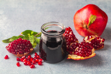 Glass bottle of pomegranate sour sauce with fresh ripe whole and split pomegranate fruit (Turkish...