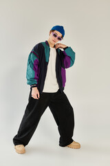 A young man poses confidently in a colorful bomber jacket within a modern studio.